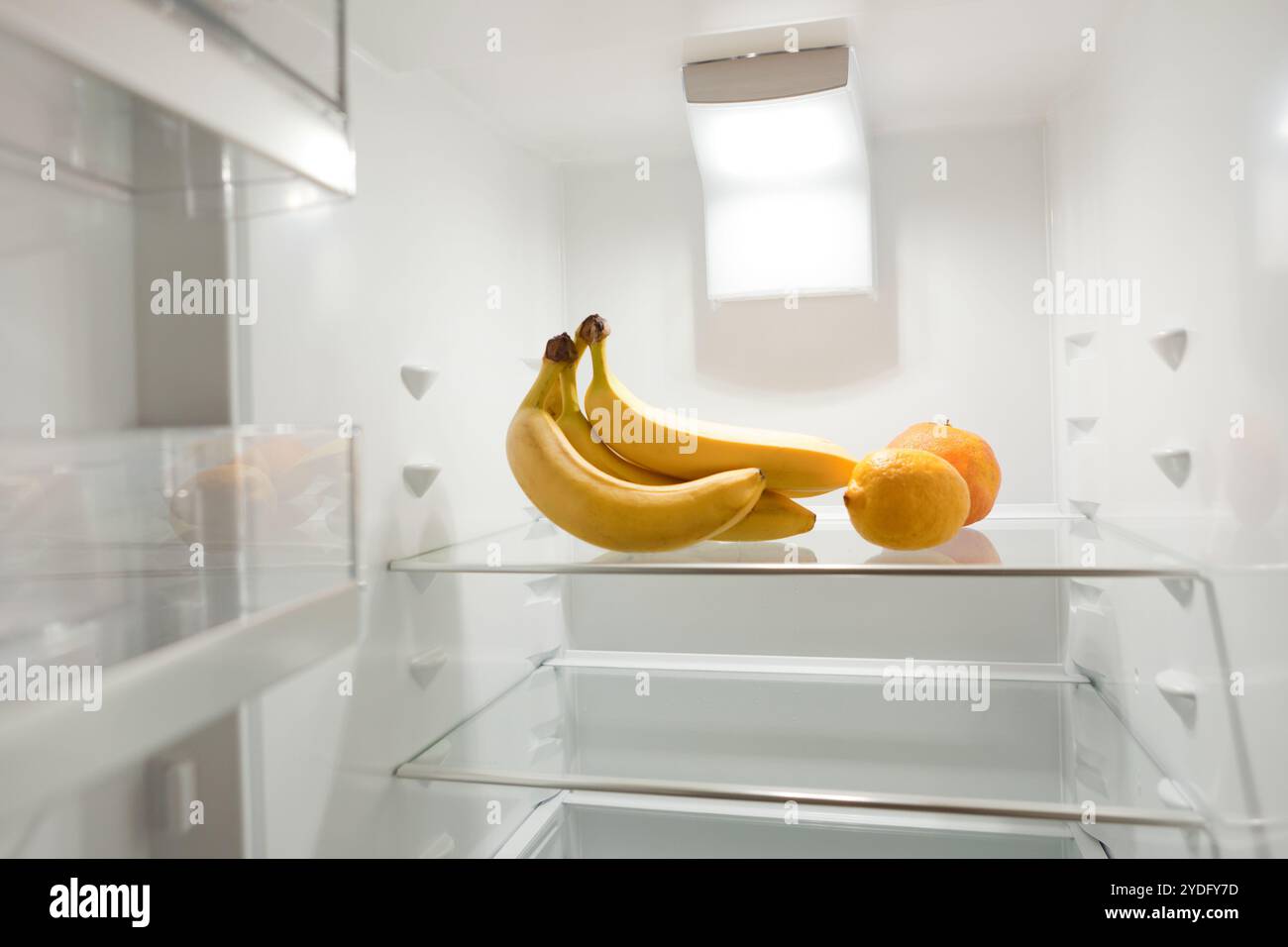 bouquet de bananes mûres dans le réfrigérateur vide. Vue à travers la porte ouverte du réfrigérateur. bananes au réfrigérateur vide Banque D'Images