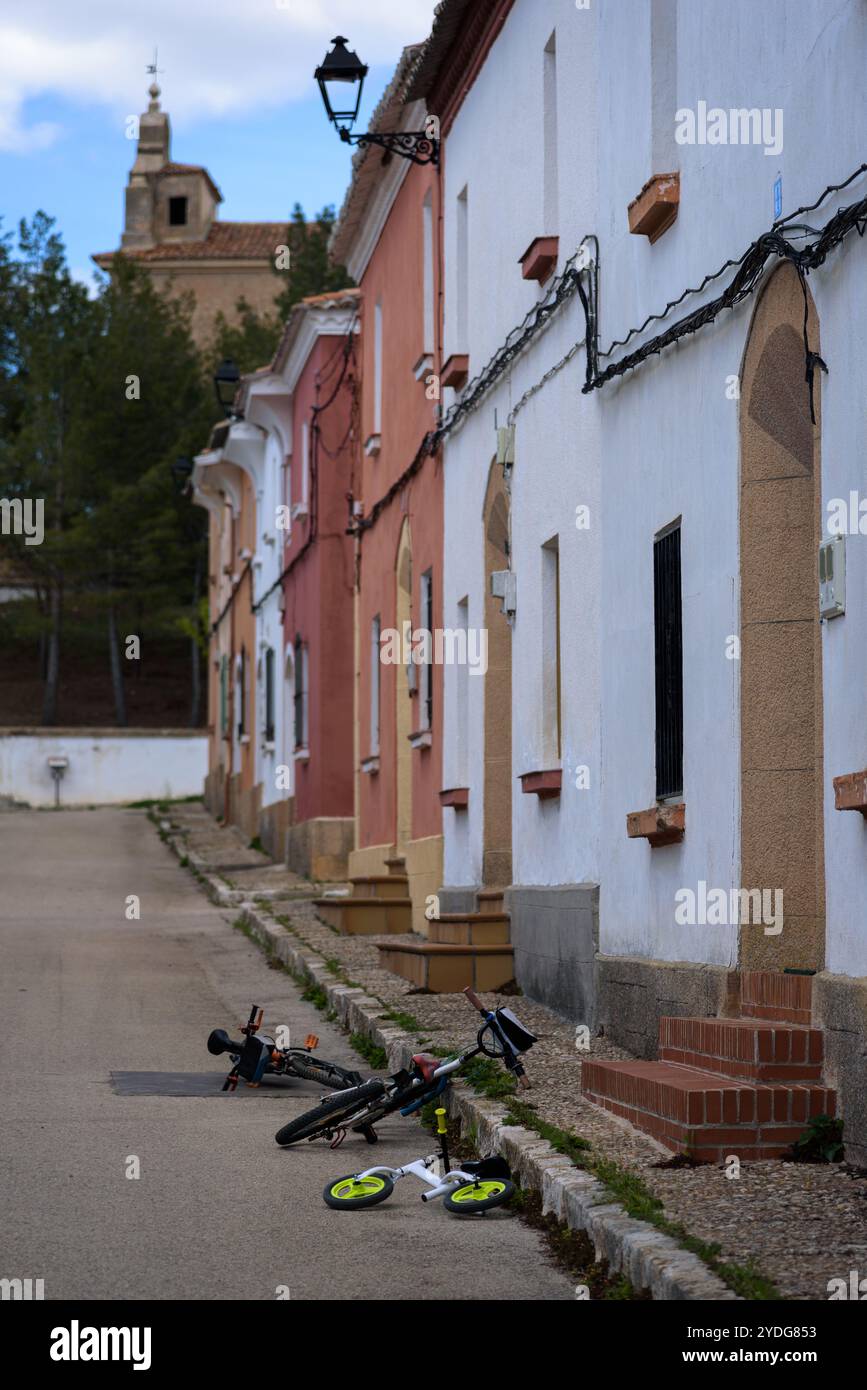 Vélos pour enfants dans une rue solitaire devant les portes des maisons, Masegoso de Tajuña, Guadalajara, Espagne Banque D'Images