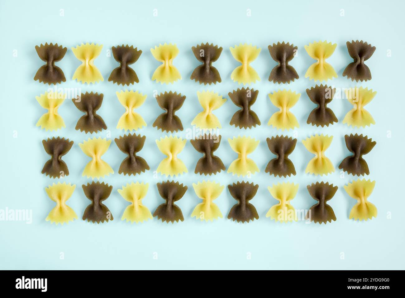 Pâtes noeud papillon disposées en rangées sur fond bleu pastel Banque D'Images