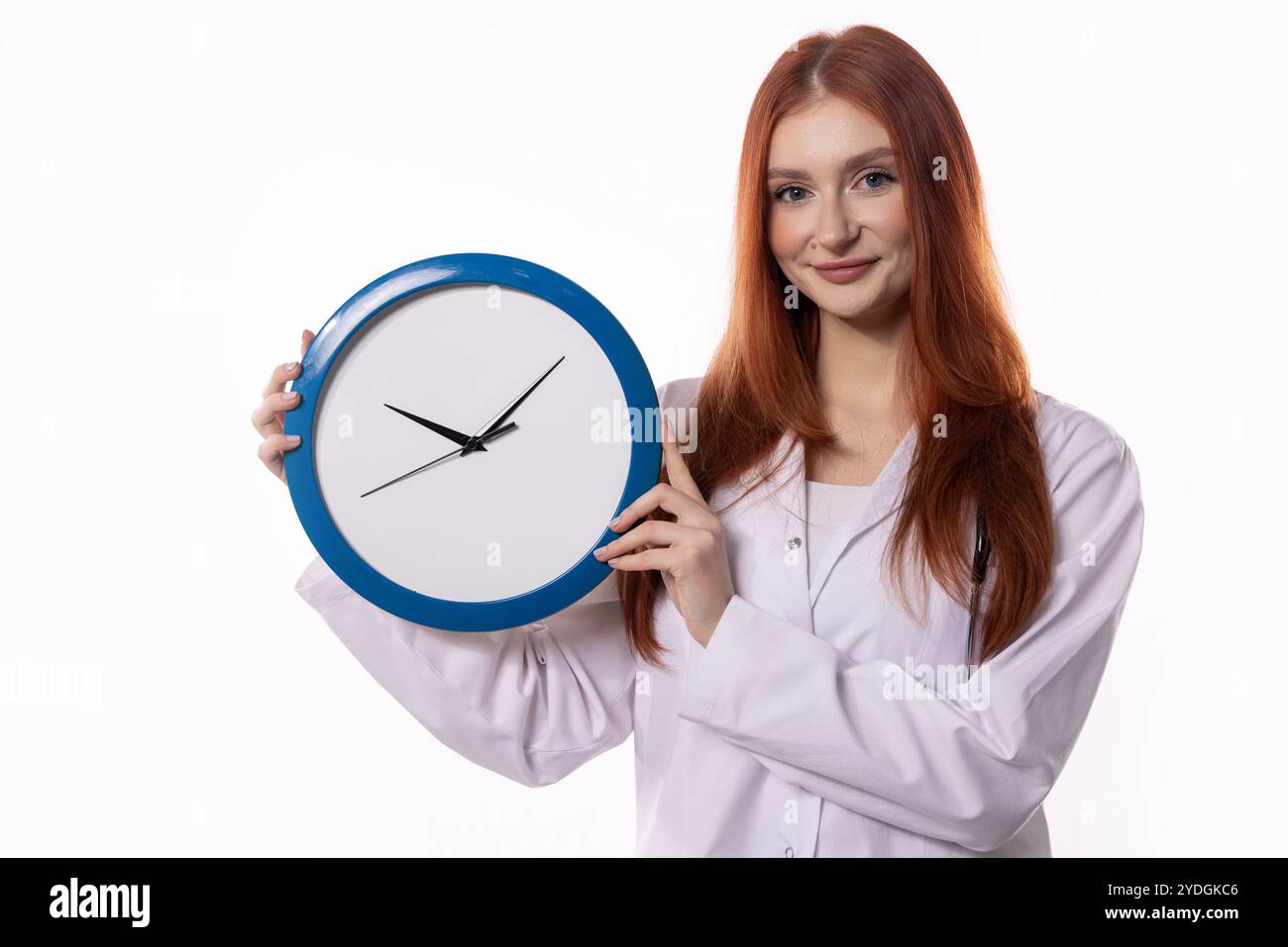 Une femme tient une horloge tout en portant une blouse de laboratoire dans un cadre professionnel officiel Banque D'Images