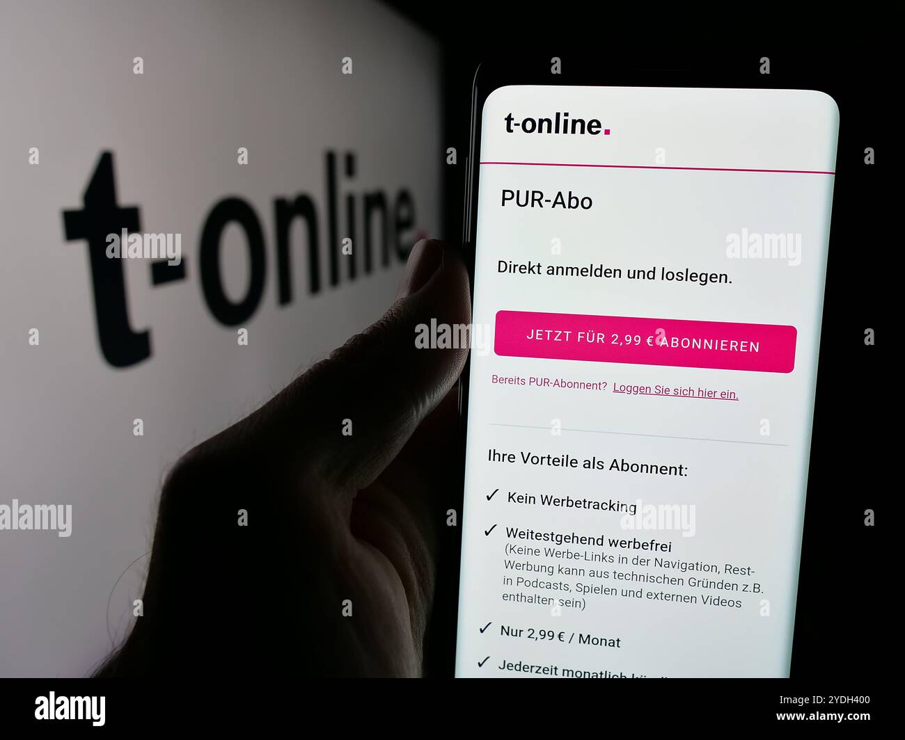 Personne tenant le téléphone portable avec la page Web de la société allemande de médias en ligne t-online sur l'écran devant le logo. Concentrez-vous sur le centre de l'écran du téléphone. Banque D'Images
