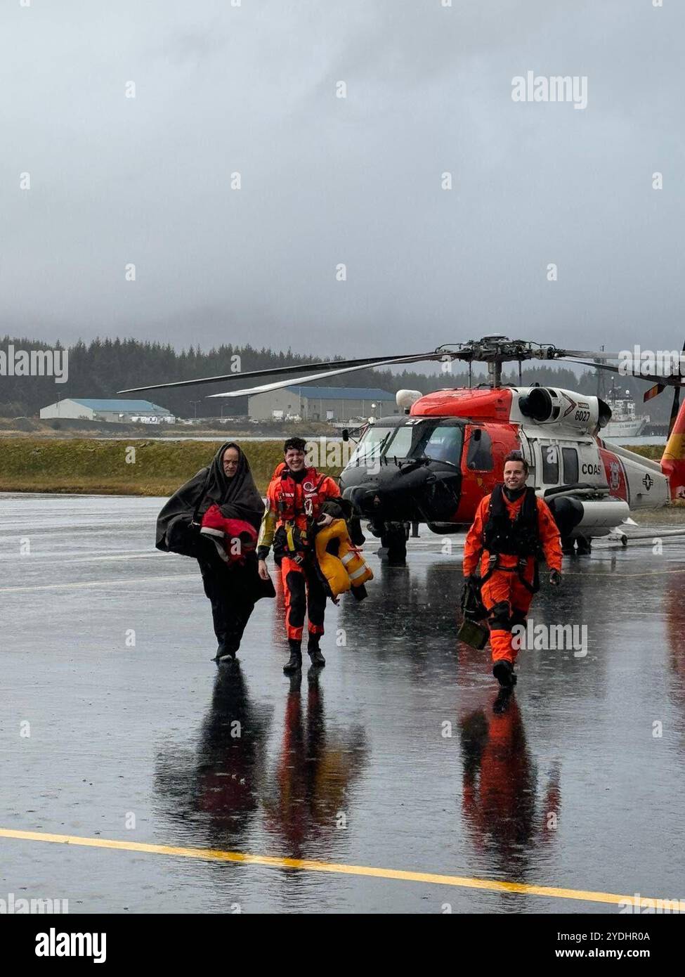 Un équipage d'hélicoptère MH-60 Jayhawk de la base aérienne de Kodiak et des survivants d'une mission de sauvetage retournent à la base Kodiak, Alaska, octobre 25, 2024. L'homme et son chat dérivaient vers les îles Barren, assaillis par les intempéries et incapables de manœuvrer, et le propriétaire du navire planifie des arrangements pour récupérer le voilier après le sauvetage. (Photo de la Garde côtière américaine par le Lt. Matt McCammon) Banque D'Images