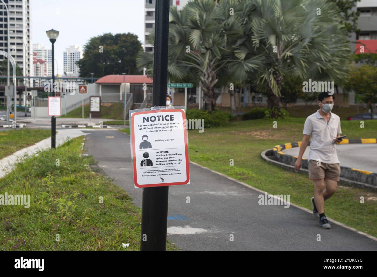 29.04.2020, Singapour, République de Singapour, Asie, Un homme portant un masque facial passe devant un panneau COVID-19 indiquant des mesures obligatoires pour poursuivre la limi Banque D'Images