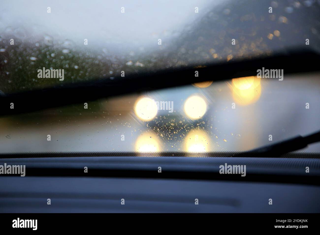 Conduite sur autoroute par forte pluie, essuie-glaces activés, faible visibilité avec phares éblouissants des véhicules venant en sens inverse Banque D'Images