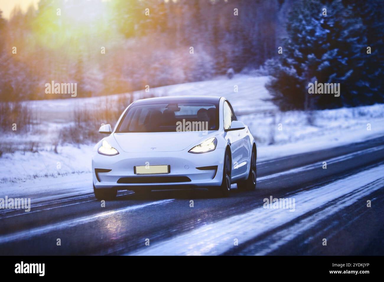 White Tesla Model 3 voiture électrique à grande vitesse sur l'autoroute en hiver au crépuscule. Salo, Finlande. 27 décembre 2021 Banque D'Images