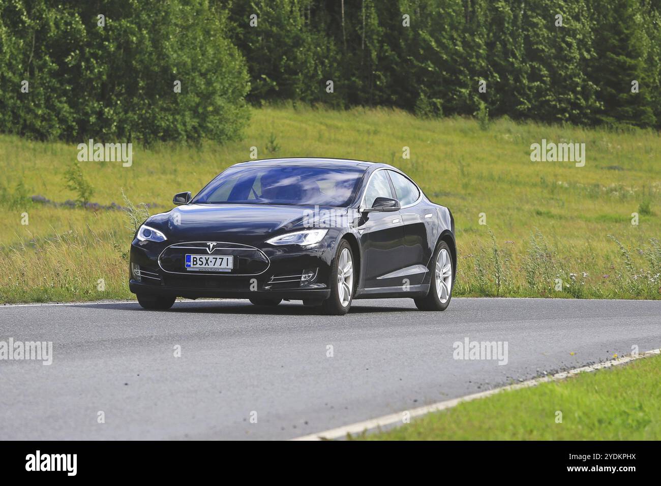 PAIMIO, FINLANDE, 17 JUILLET 2016 : le véhicule électrique Tesla Model S noir se déplace sur la route rurale à travers la nature finlandaise verte en été Banque D'Images