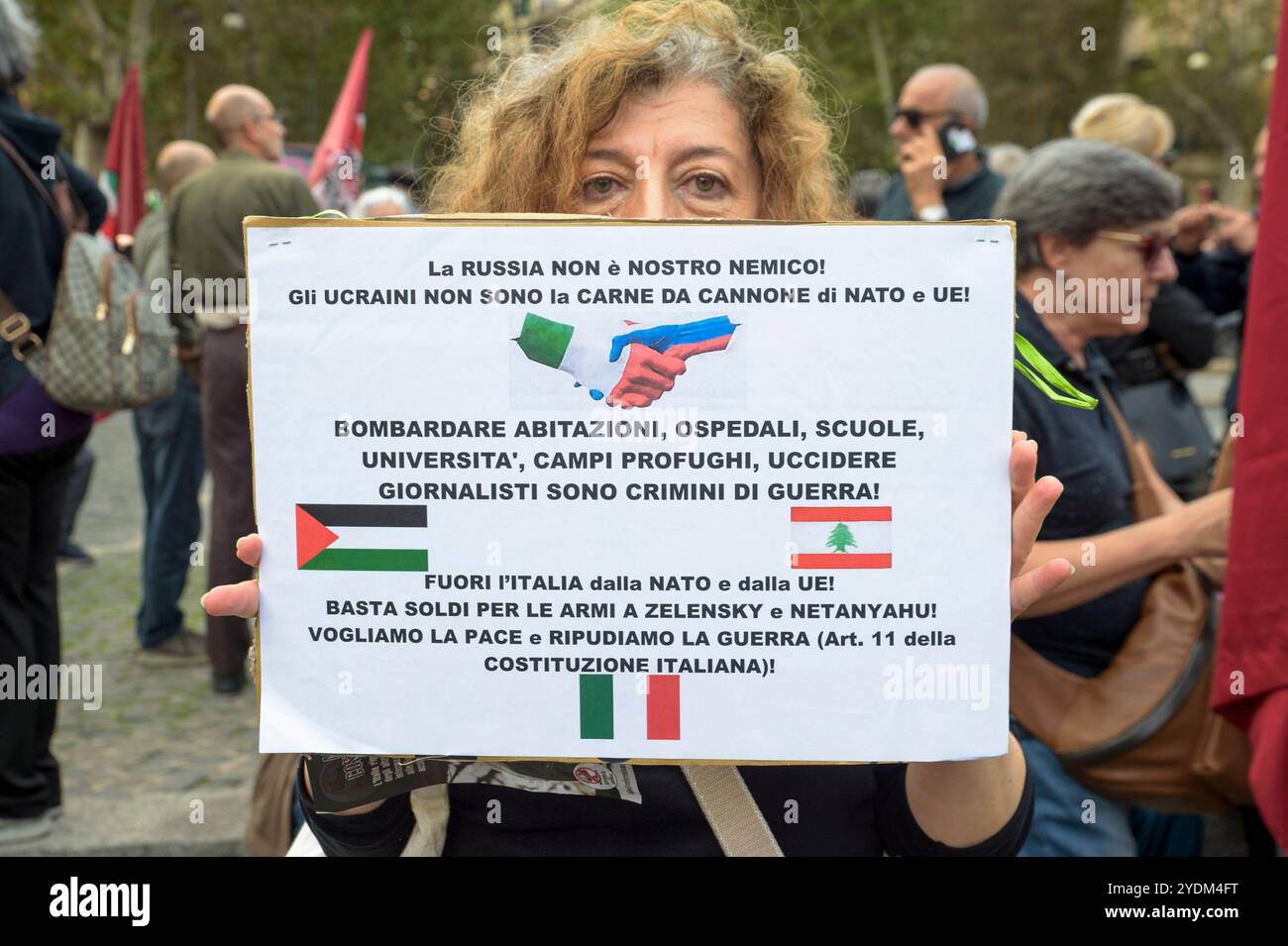 Rome, Italie. 26 octobre 2024. Un manifestant brandit une pancarte avec les slogans "la Russie n'est pas notre ennemi!", "les Ukrainiens ne sont pas de la chair à canon pour l'OTAN et l'UE", "bombardant des maisons, des hôpitaux, des écoles, des universités, camps de réfugiés, assassinats de journalistes sont des crimes de guerre!», «L'Italie hors de l'OTAN», «plus d'argent pour les armes pour Zelensky et Netanyahu», «nous voulons la paix et nous répudions la guerre» lors de la manifestation contre les guerres en cours et pour réitérer que «˜l'Italie répudie la guerre» organisée par le parti politique anti-establishment démocratie populaire souveraine à Rome. (Crédit image : © Marcello Valeri/ZUMA Pre Banque D'Images