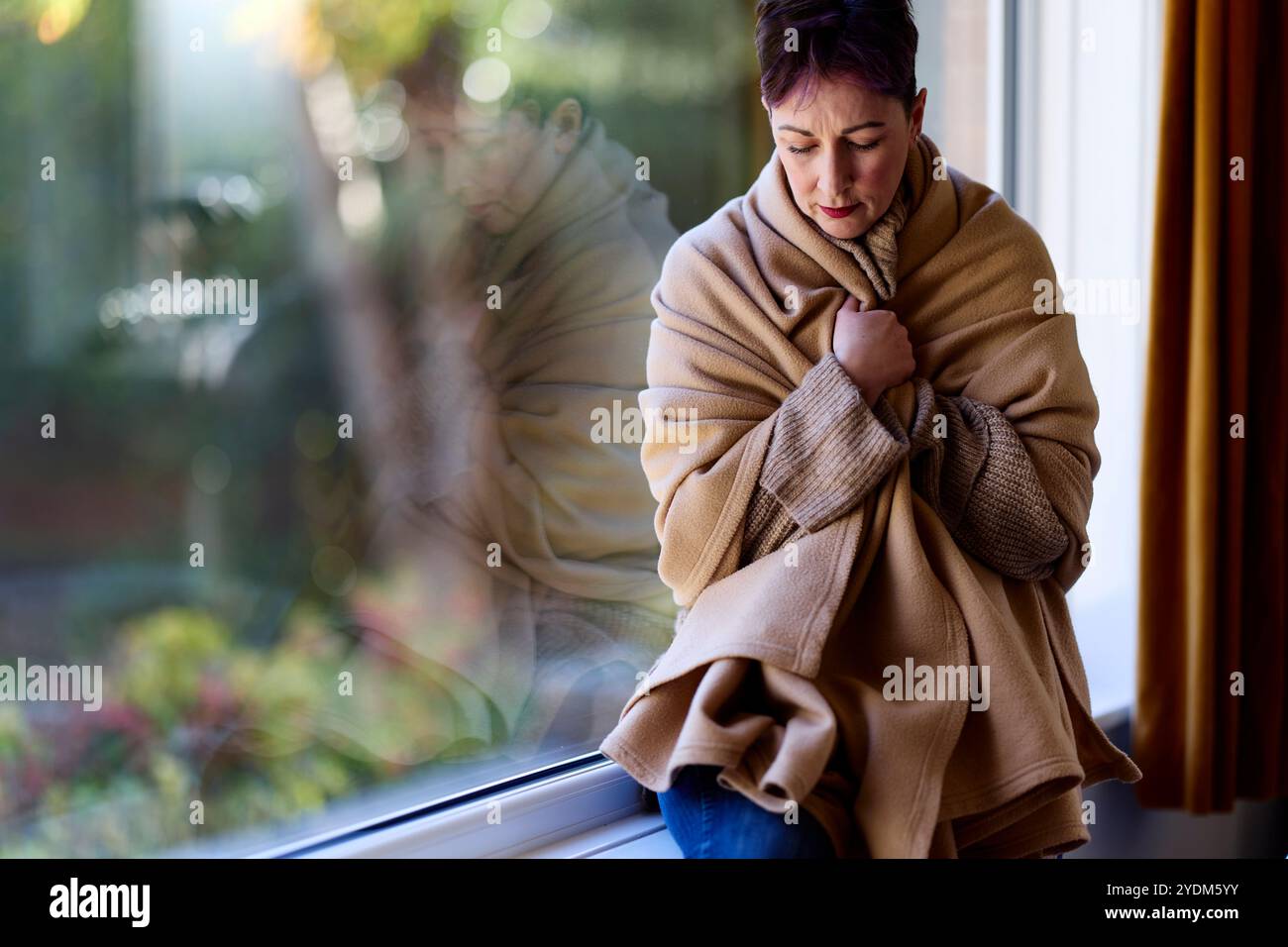 Femme enveloppée dans une couverture gardant au chaud Banque D'Images