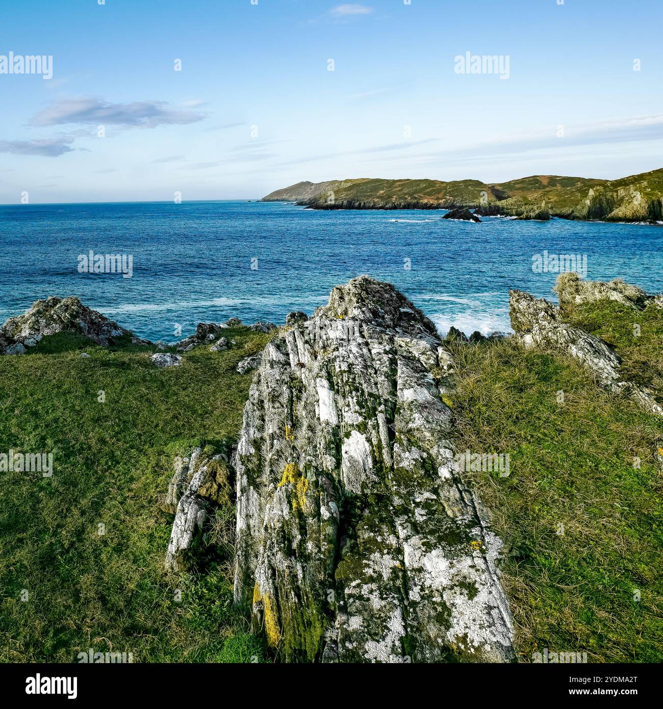 Ce littoral pittoresque présente des formations rocheuses escarpées surplombant les eaux bleues scintillantes sous un ciel lumineux et ensoleillé. L'atmosphère paisible envahit Banque D'Images