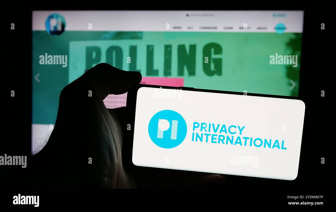 Personne tenant un téléphone portable avec le logo de Britih Charity Privacy International (PI) sur l'écran devant la page Web. Concentrez-vous sur l'affichage du téléphone. Banque D'Images