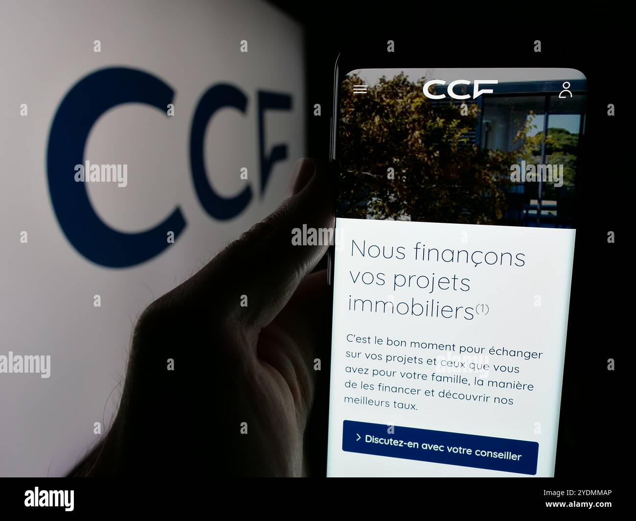 Personne tenant un smartphone avec la page web de la société crédit commercial de France (CCF) sur l'écran devant le logo. Concentrez-vous sur le centre de l'écran du téléphone. Banque D'Images