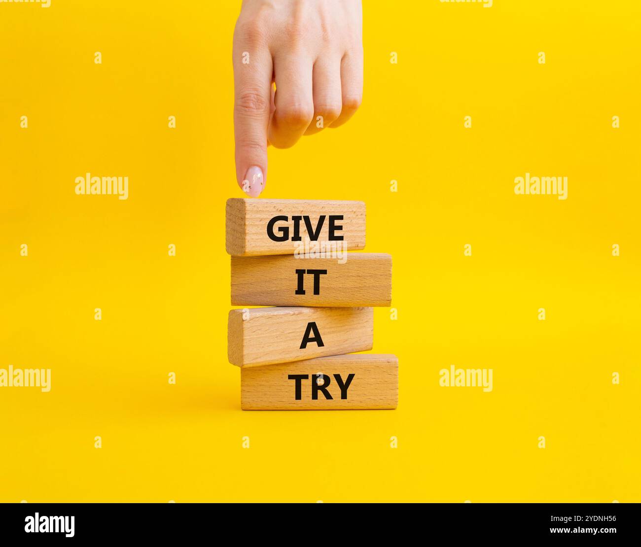 Donnez-lui un symbole essayer. Les mots conceptuels lui donnent un essai sur des blocs de bois. Beau fond jaune. Main d'homme d'affaires. Et donnez-lui un concept d'essai. Banque D'Images