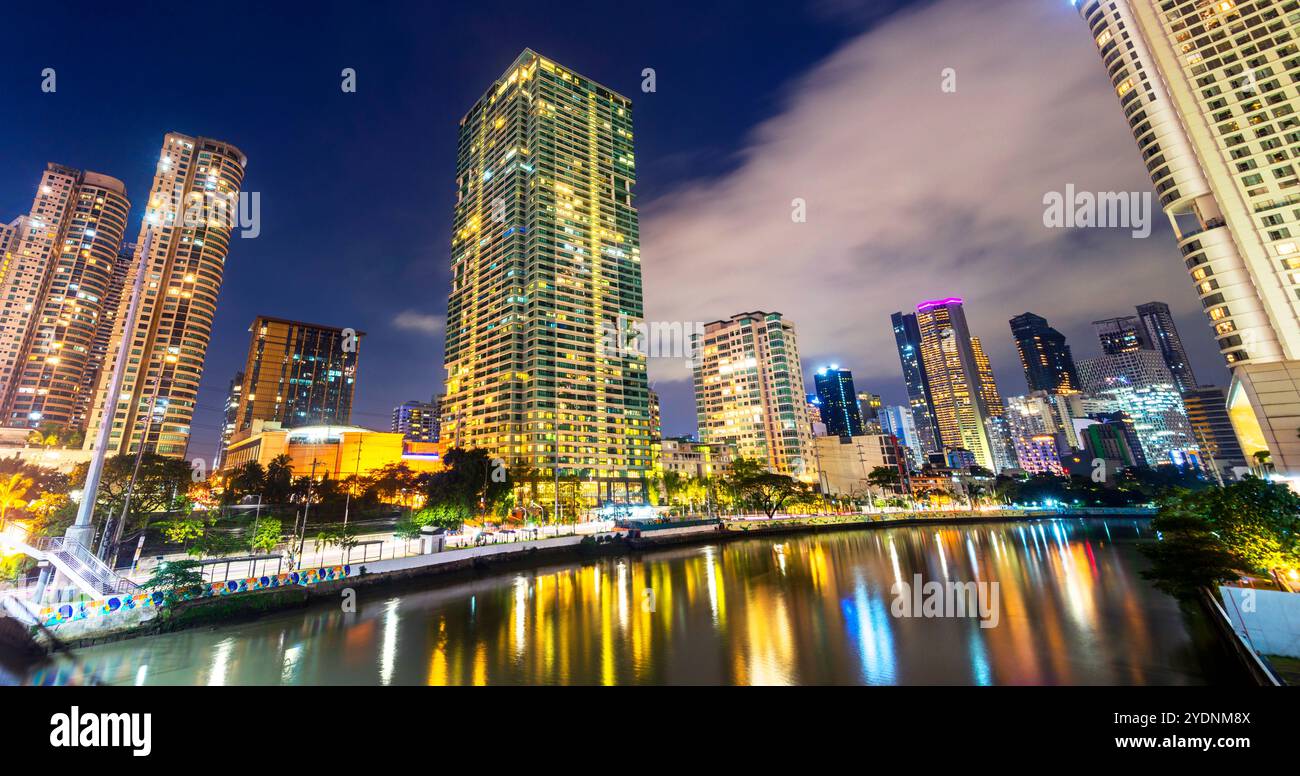 Bordant la rivière principale, traversant l'un des quartiers centraux les plus haut de gamme de Manille, les condos et les immeubles de bureaux s'allument, brillamment illuminés, R Banque D'Images