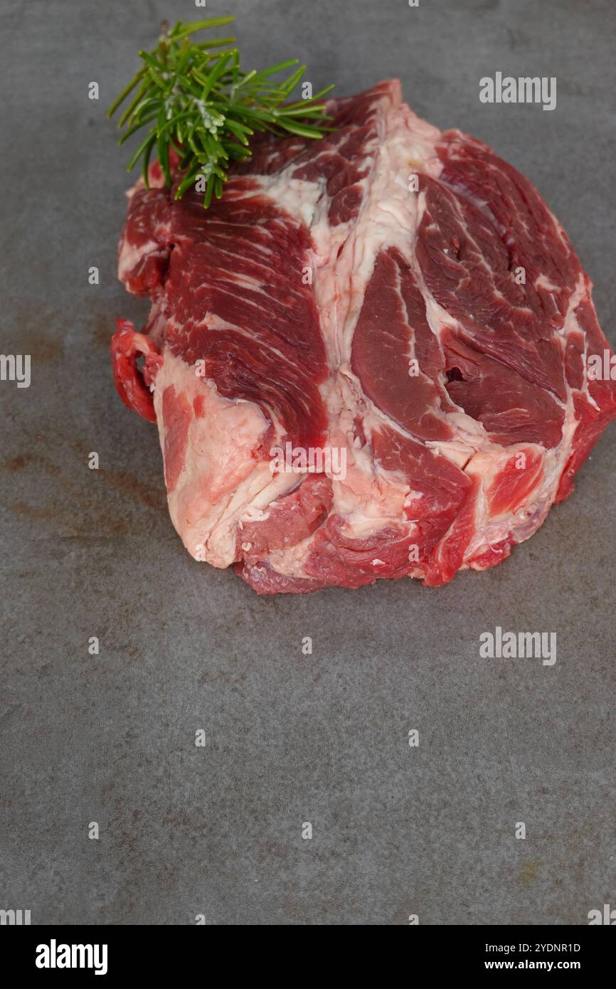 Rôti de chuck de bœuf cru frais avec garniture de romarin frais Banque D'Images