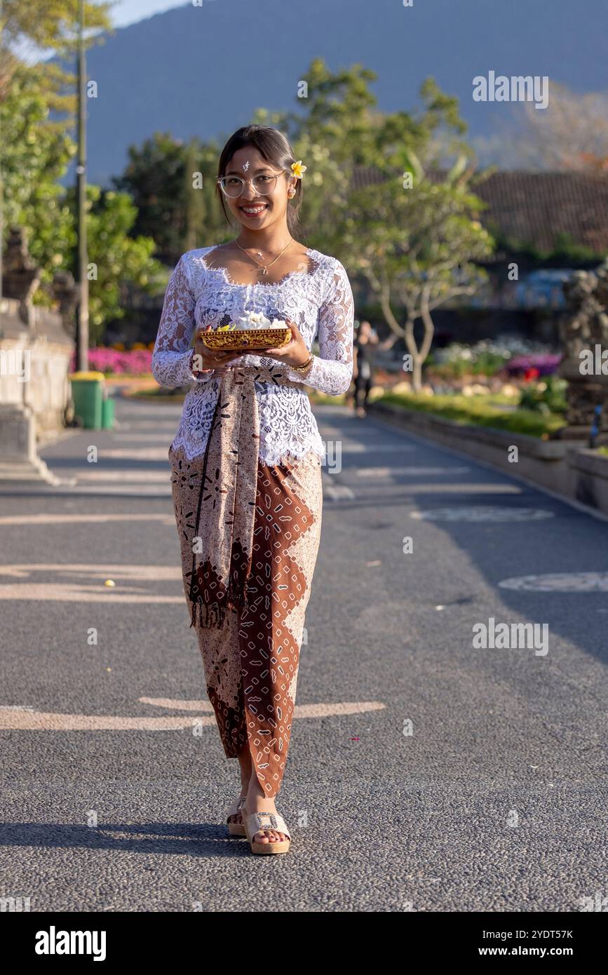 Bali, Indonésie - 25 septembre 2024 - famille balinaise vêtue de vêtements traditionnels, debout à l'entrée d'un temple, offrant des prières et des honneurs Banque D'Images