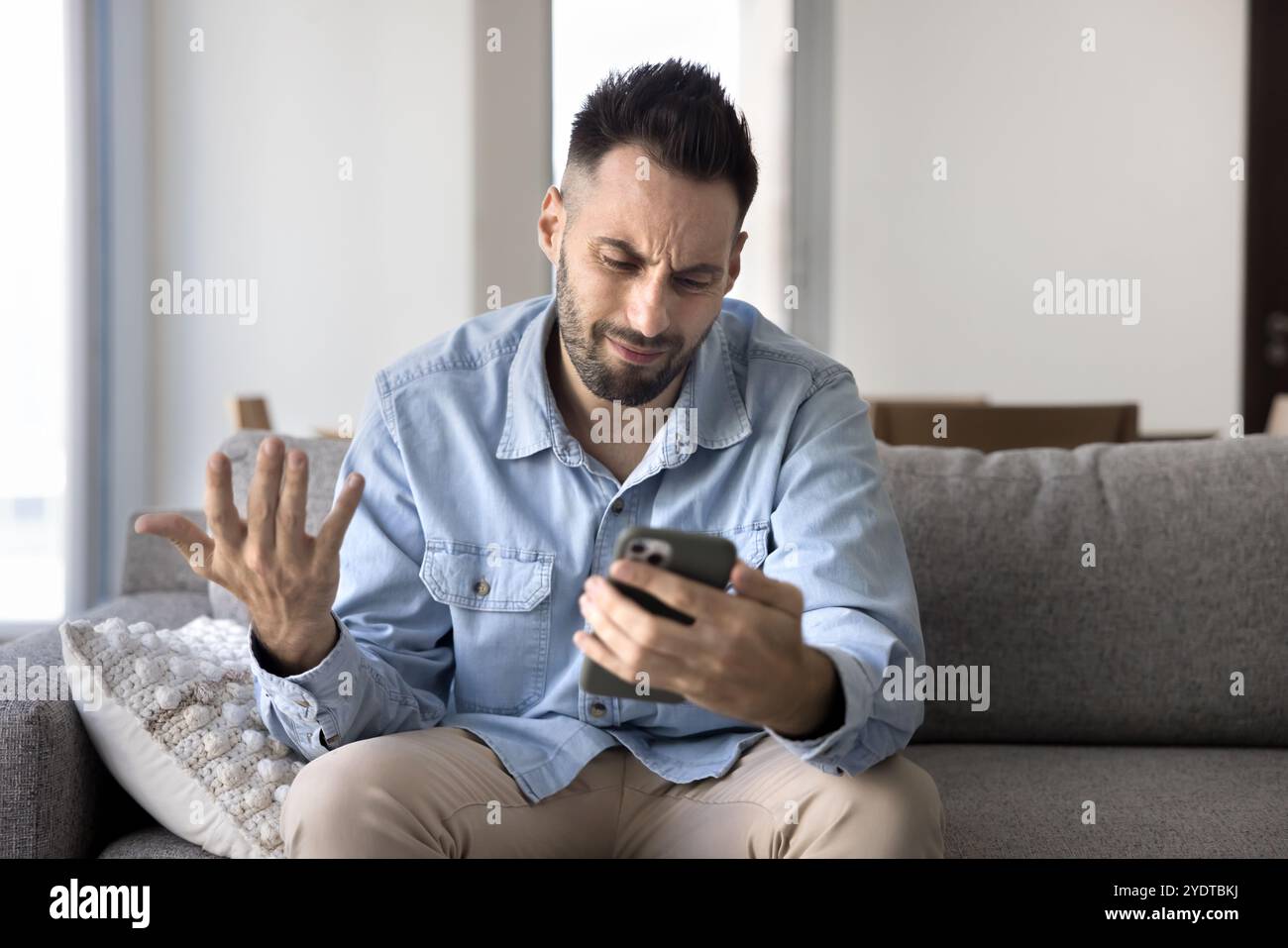 Nerveux frustré jeune homme latin utilisant un smartphone, ayant des problèmes Banque D'Images