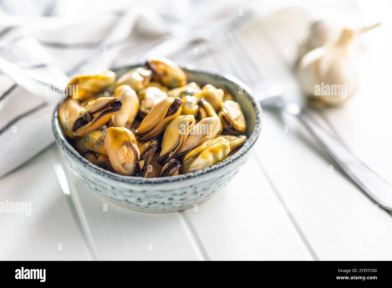 Viande de moules décortiquées dans un bol sur une table blanche Banque D'Images