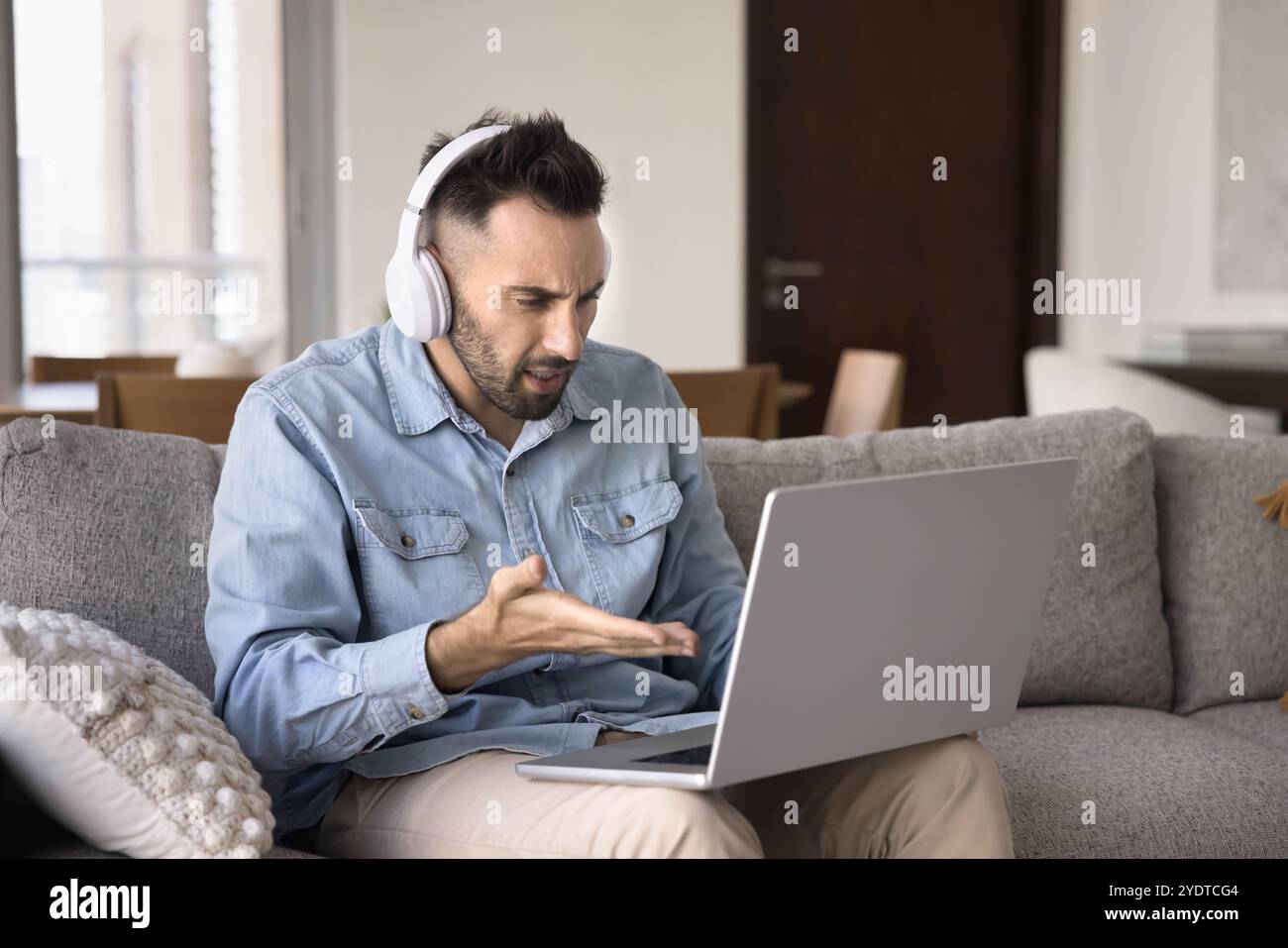 Nerf confus latin freelance homme dans des écouteurs regardant l'ordinateur portable Banque D'Images