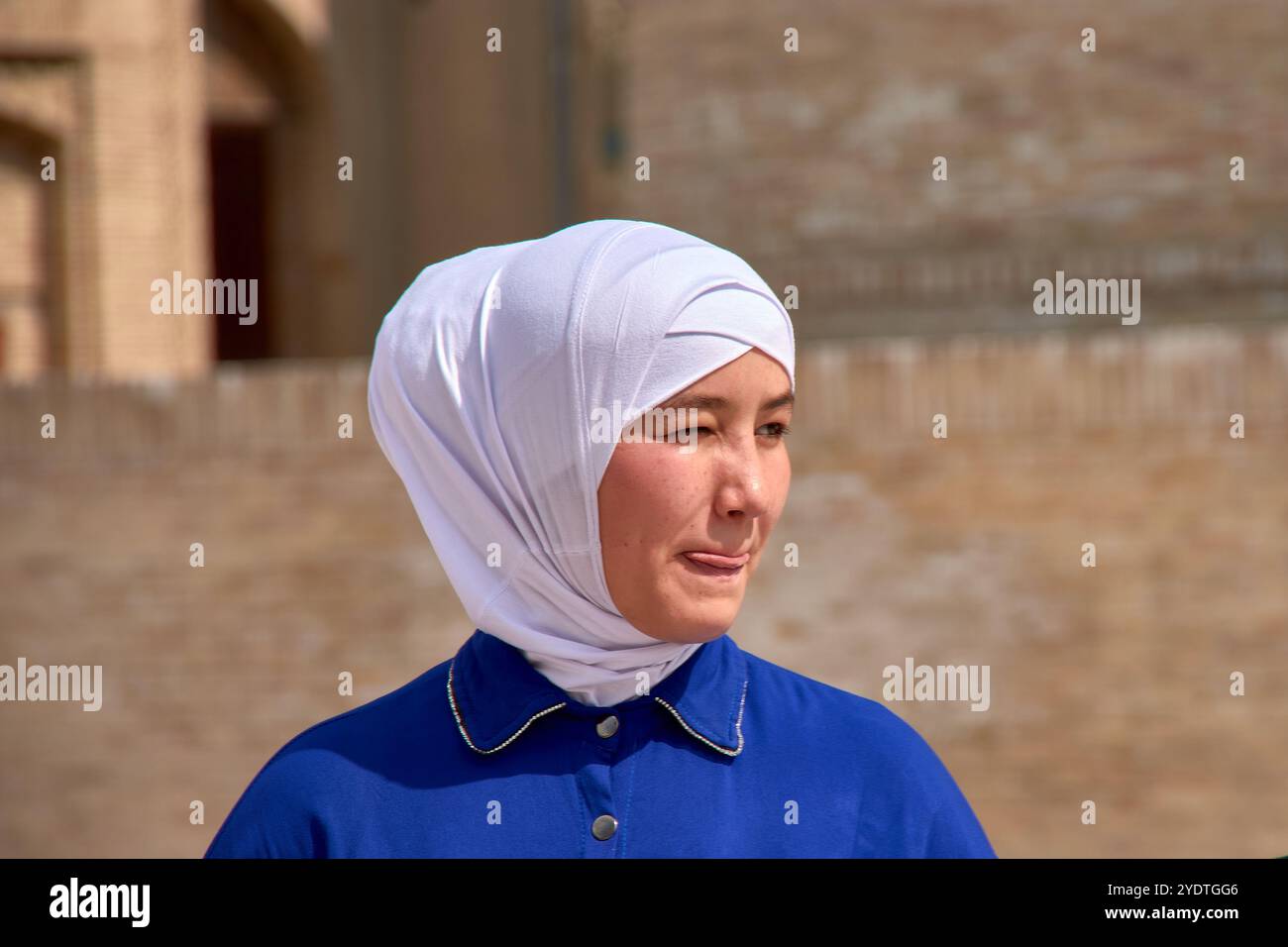 Boukhara, Ouzbékistan ; septembre,19,2024:une jeune femme ouzbèke exsudant l'élégance avec sa combinaison frappante d'un voile blanc et d'une robe bleue vibrante Banque D'Images