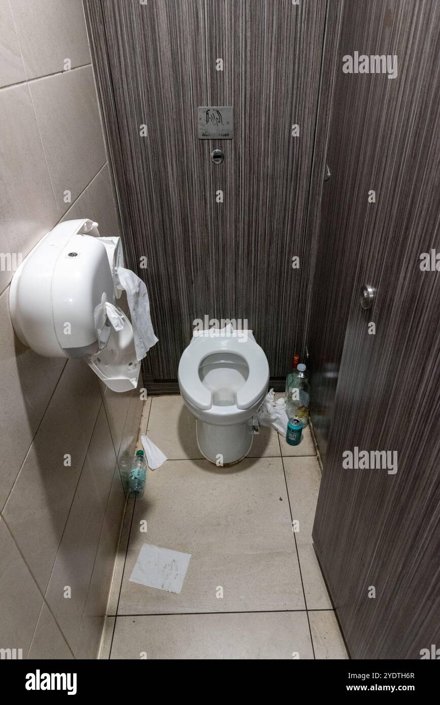 Toilettes cubiques dans la gare de Liverpool Street avec des bouteilles d'alcool et d'eau vides et des canettes sur le sol, avec du papier et des distributeurs de rouleaux de papier hygiénique endommagés Banque D'Images
