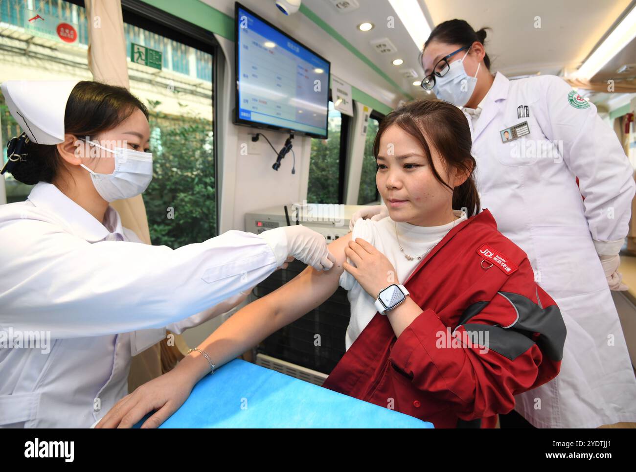 GUIYANG, CHINE - 28 OCTOBRE 2024 - Un travailleur médical donne gratuitement le vaccin contre la grippe à une femme courrier de Jingdong Express sur un véhicule de vaccination mobile Banque D'Images