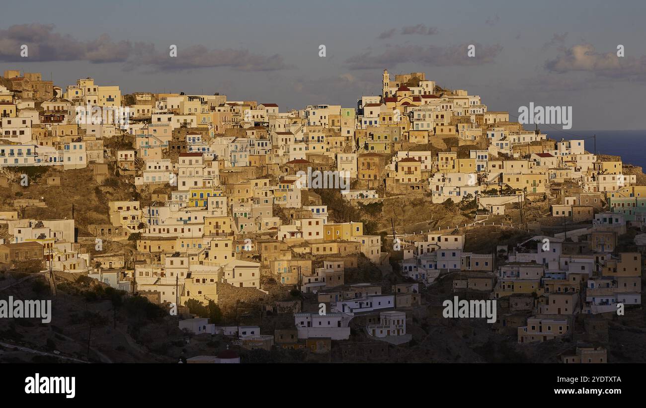 Une ville de colline avec des maisons étroitement construites au lever du soleil, l'ombre tombe sur certaines parties des bâtiments, village de montagne coloré, lumière du matin, Olymbos, Ka Banque D'Images