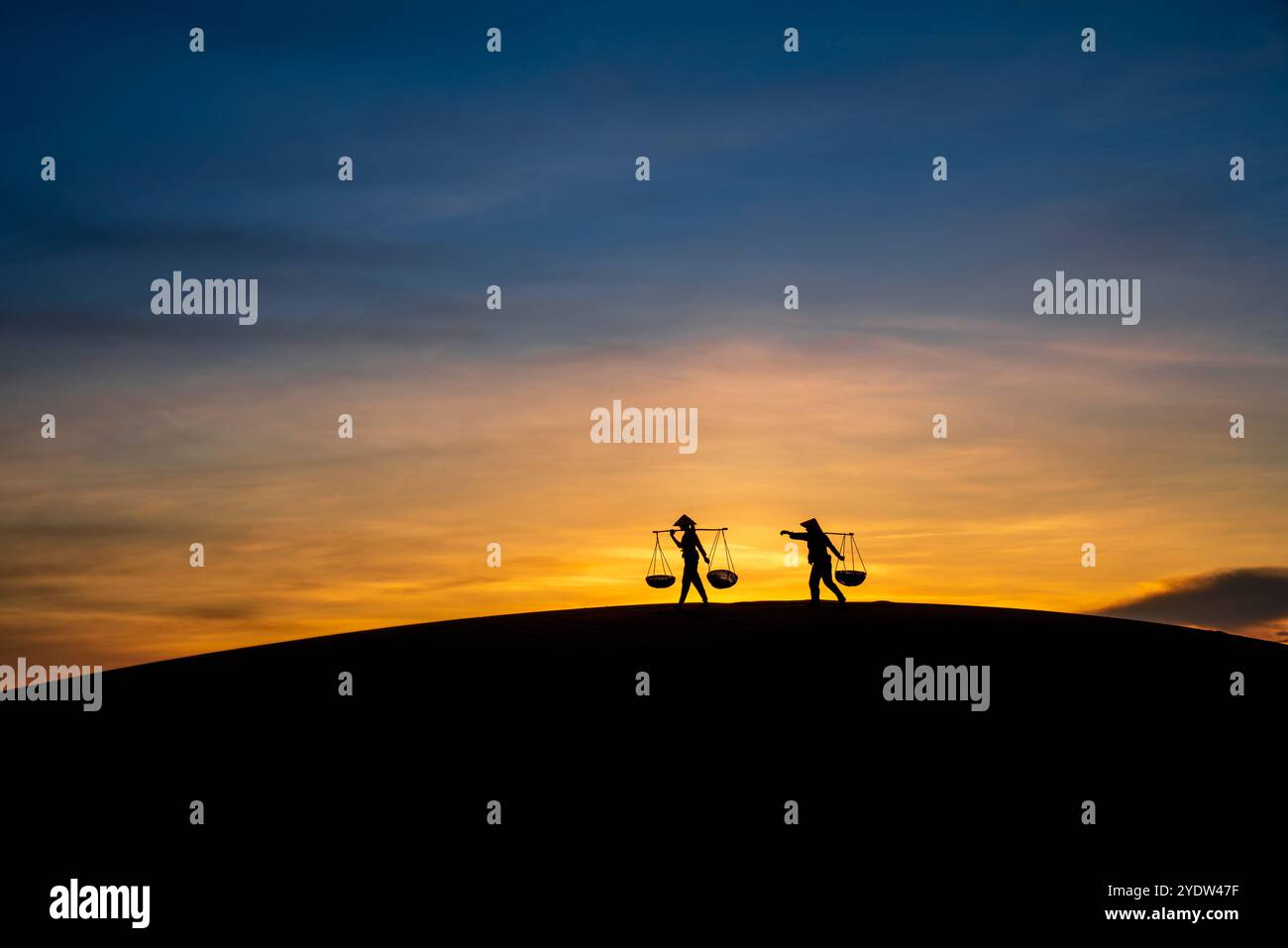Silhouette de deux personnes portant des paniers au coucher du soleil, colline de sable Nam Cuong à Ninh Thuan, Vietnam, Indochine, Asie du Sud-est, Asie Banque D'Images