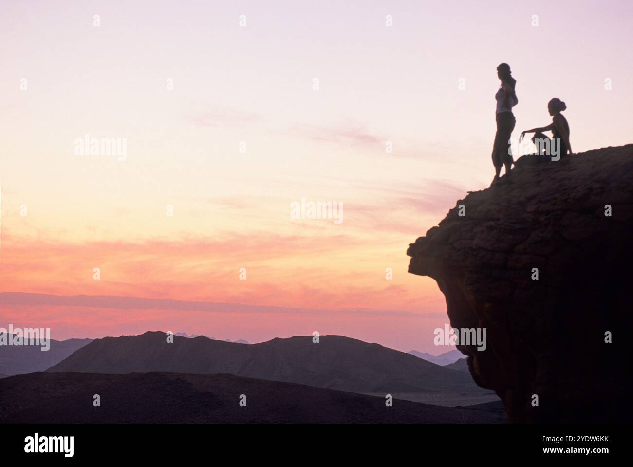 Deux femmes assises sur un rocher profitant du coucher du soleil dans le désert de Wadi Rum, Jordanie, moyen-Orient Banque D'Images