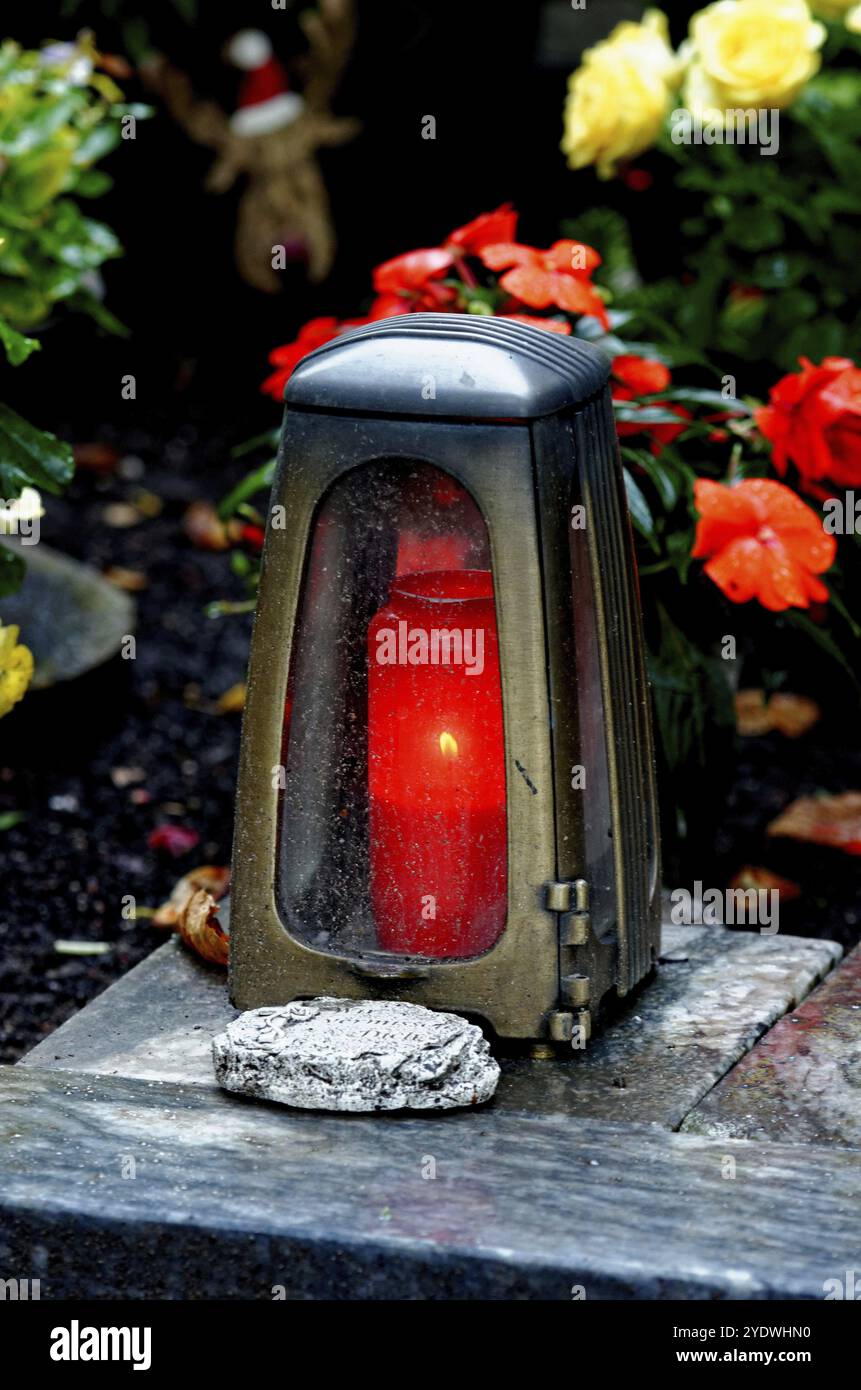 Vive la lumière avec bougie allumée sur une tombe avec des fleurs sur une soirée d'automne Banque D'Images