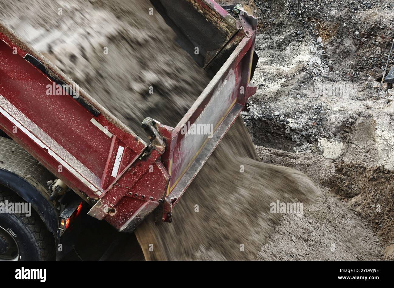 Un camion à benne basculante décharge une charge de sable sur un chantier de construction Banque D'Images