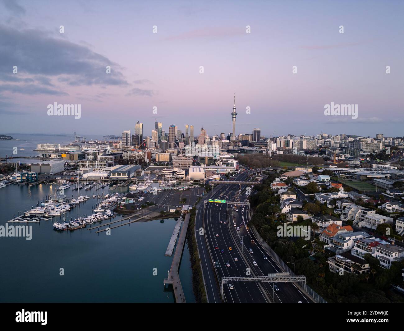 Auckland, Nouvelle-Zélande : vue aérienne spectaculaire de l'autoroute Westhaven menant à la ligne d'horizon du centre-ville d'Auckland au coucher du soleil en Nouvelle-Zélande. Banque D'Images