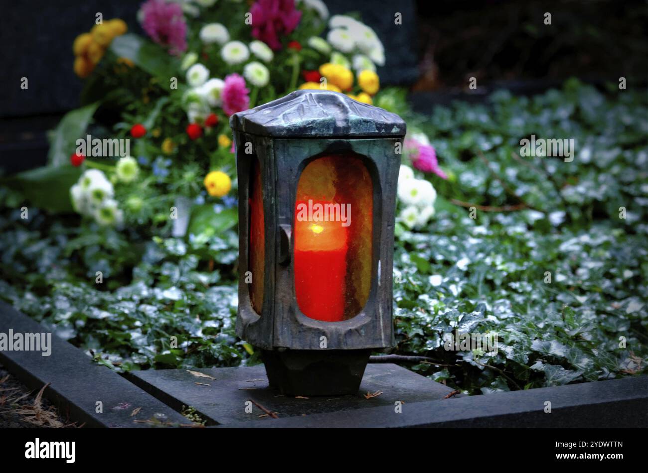 Vive la lumière avec bougie allumée sur une tombe avec des fleurs sur une soirée d'automne Banque D'Images