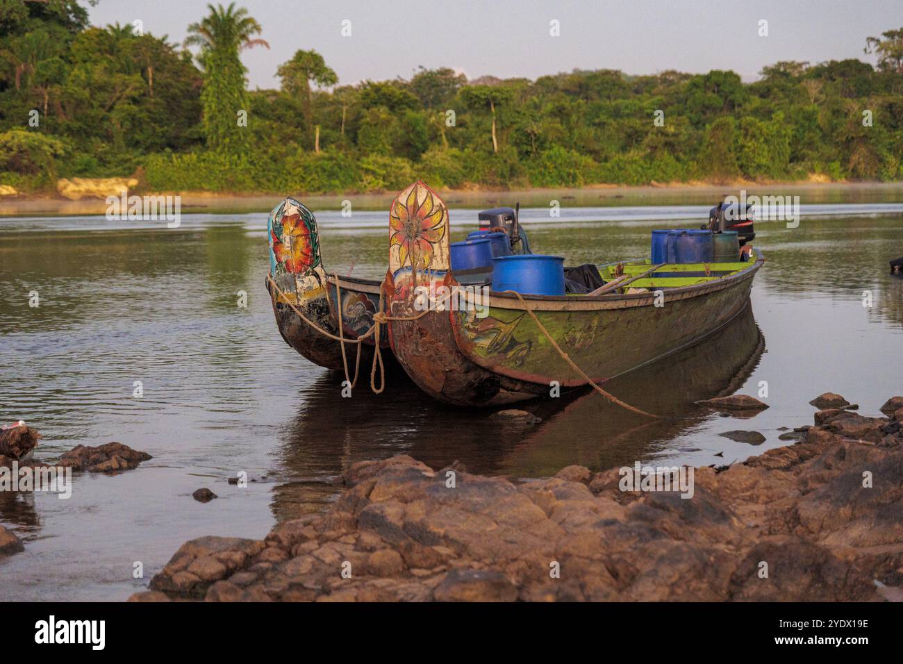 Matinée sereine dans la région de Lawa au Suriname, où les bateaux colorés reposent sur des eaux calmes, entourés par la majestueuse forêt tropicale. Une véritable évasion tranquille. Banque D'Images