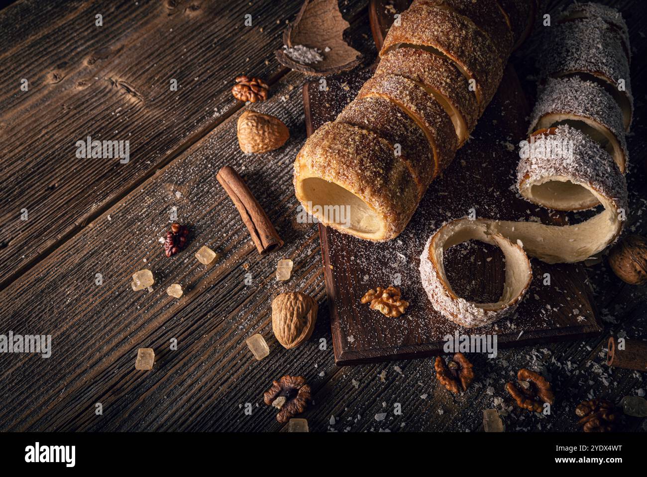 Gâteau de cheminée fraîchement cuit sur une planche de bois avec des noix, du sucre brun et des bâtonnets de cannelle, créant une scène confortable et délicieuse Banque D'Images