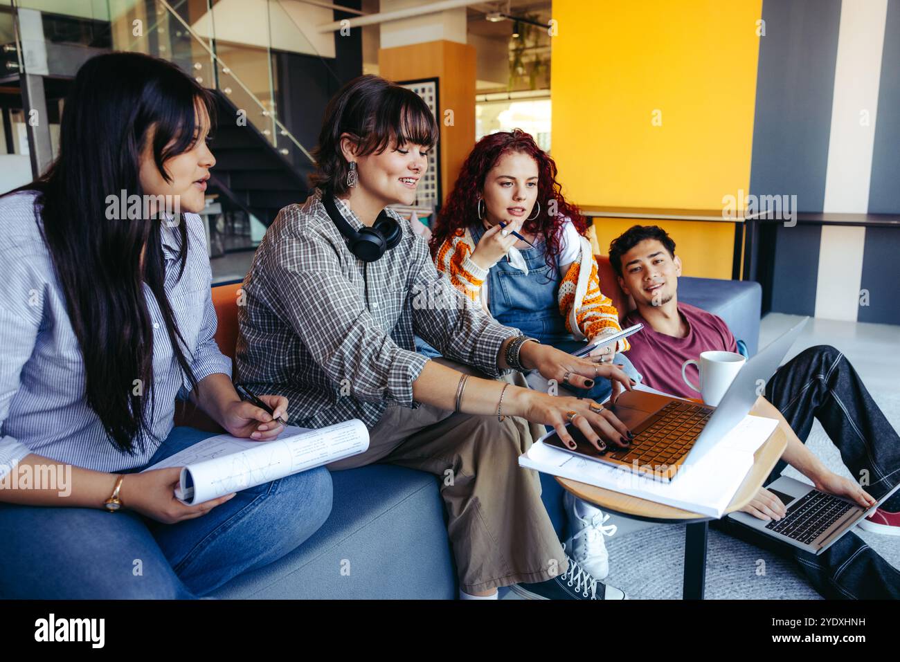 Un groupe occasionnel de jeunes adultes s’engage dans un projet collaboratif utilisant des ordinateurs portables dans un bureau contemporain, mettant l’accent sur le travail d’équipe et la créativité. Banque D'Images