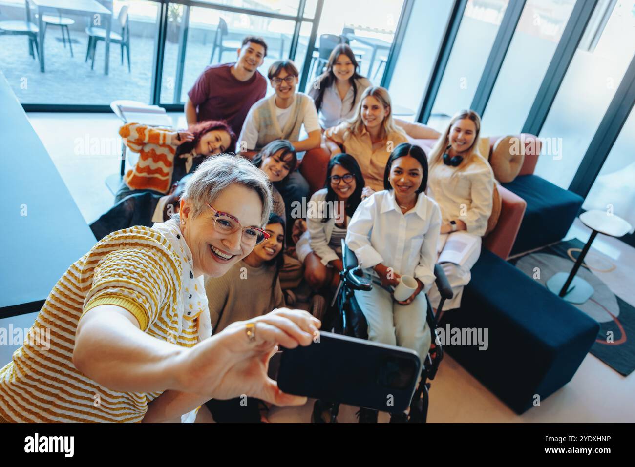Un groupe diversifié d'étudiants et leur mentor capturent un selfie heureux, mettant en valeur le travail d'équipe, l'amitié et l'apprentissage dans un universitaire contemporain Banque D'Images