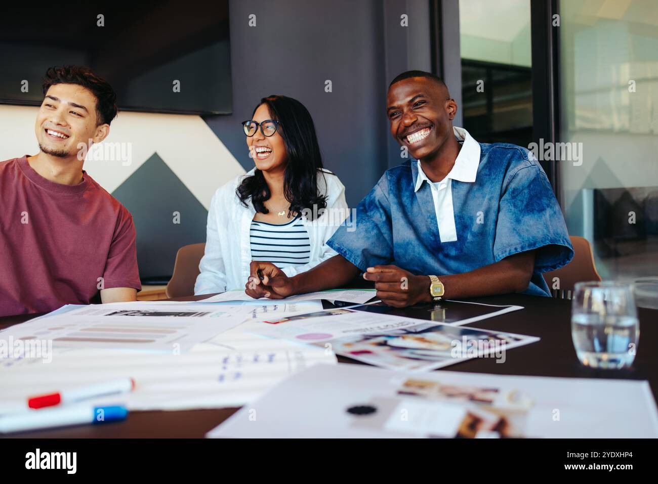 Jeunes diplômés joyeux se réunissent dans une atmosphère animée, célébrant leur succès. L'image capture un travail d'équipe diversifié, mettant en valeur l'énergie positive et h. Banque D'Images
