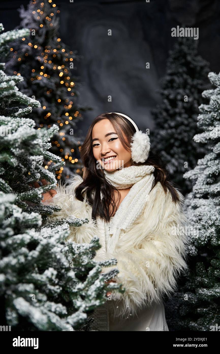 Un individu joyeux profite d'une atmosphère festive, entouré d'arbres givrés et de lumières. Banque D'Images