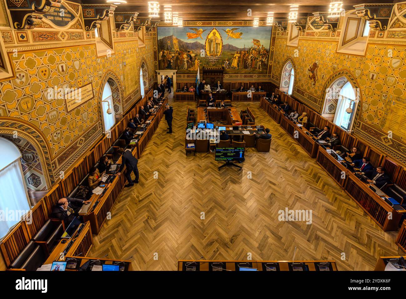 Parlement de Saint-Marin (Consiglio Grande e Generale). 60 membres du parlement sont élus pour une période législative de cinq ans. Ils exercent leur mandat à titre honorifique et ont habituellement d'autres professions principales. La peinture d'Emilio Retrosi (apparaît à son peuple un Marinus) sur l'en-tête. Palazzo Pubblico della Repubblica di San Marino. Session parlementaire dans la salle plénière de Saint-Marin. Contrada del Pianello, Città di San Marino, Saint-Marin Banque D'Images