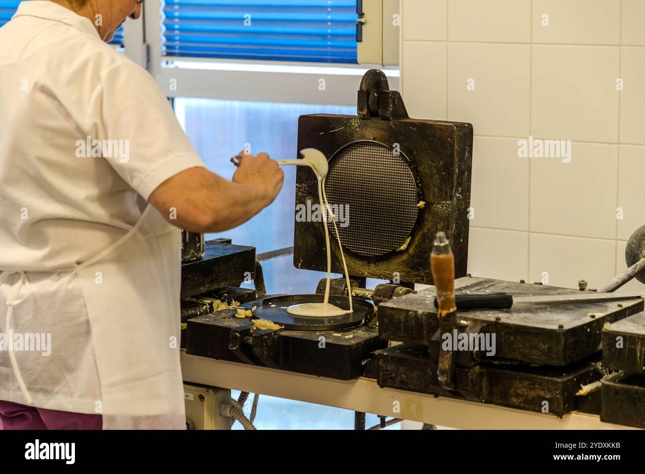 La pâte liquide à base de farine, d'huile, d'eau et de lait est cuite dans de vieux gaufriers en fonte pendant quatre minutes, Torta Tre Monti, Saint-Marin. Un employé de la Serenissima verse de la pâte sur un gaufrier. Les signes d'utilisation révèlent qu'il s'agit encore de la première génération de gaufriers, avec laquelle la production industrielle a commencé en 1942. Via XXV Marzo, Domagnano, Saint-Marin Banque D'Images