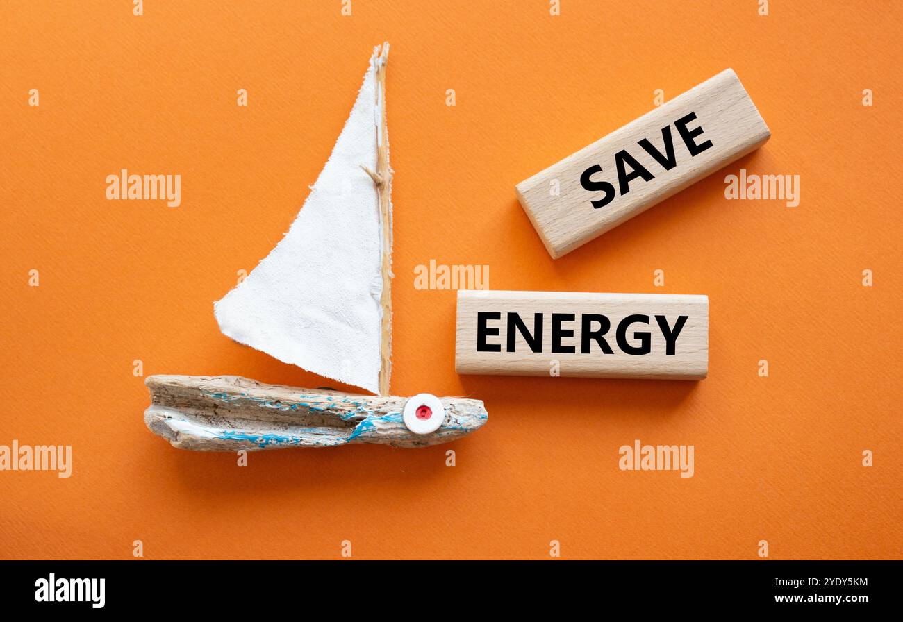 Symbole Economie d'énergie. Blocs en bois avec mots Save Energy. Beau fond orange avec bateau. Business and Save Energy concept. Copier l'espace. Banque D'Images