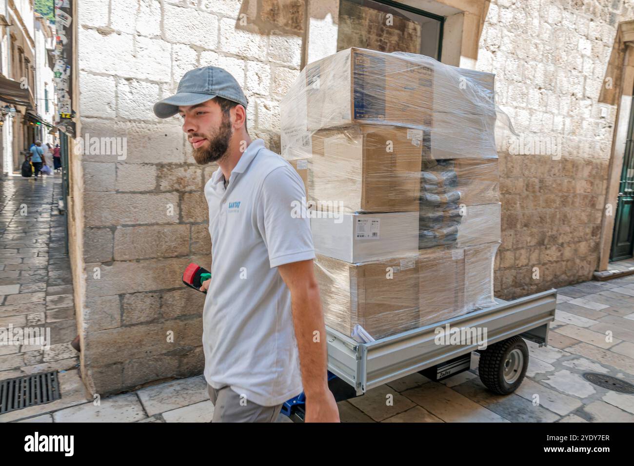 Dubrovnik Croatie, vieille ville Stari Grad Ragusa ville fortifiée, rue Ulica od Puca, travailleur de l'homme, tirant le chariot électrique de guidage, boîtes de livraison, Sanitat employer Banque D'Images