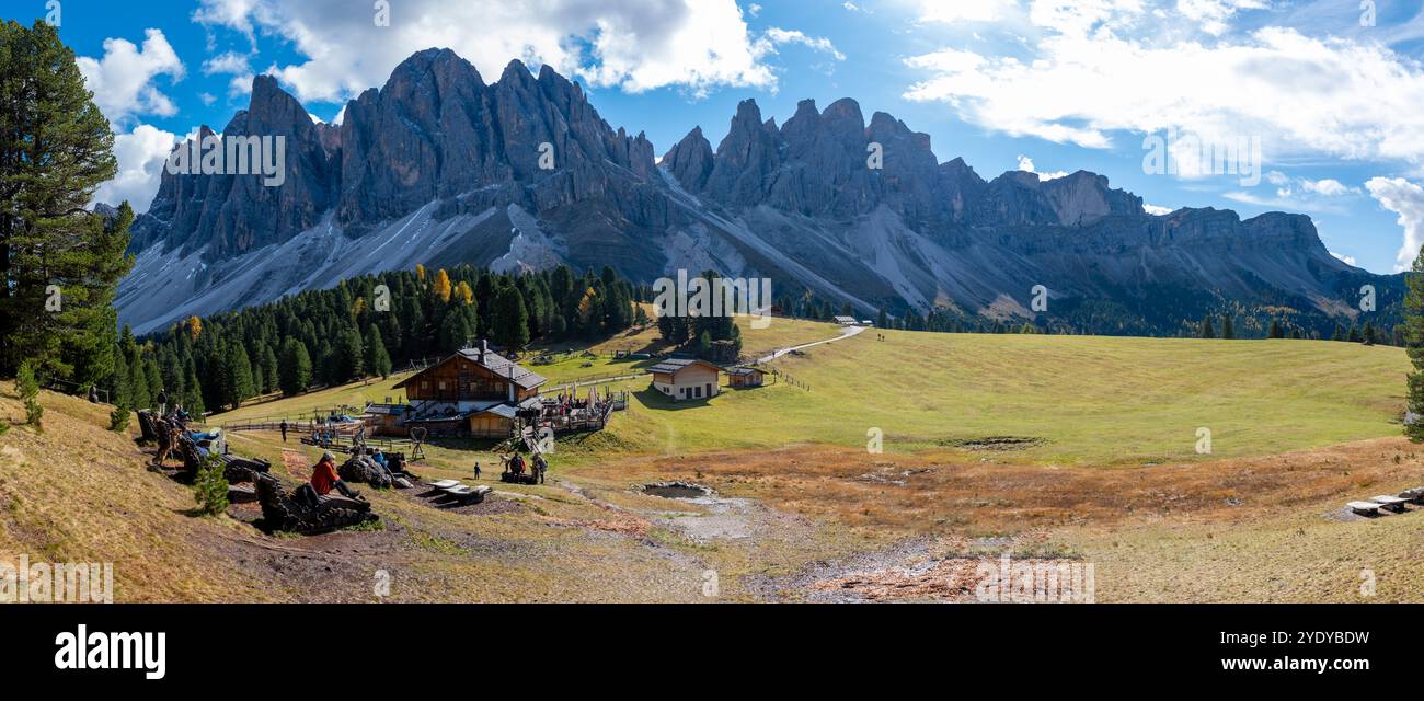 Sous un ciel bleu clair, les visiteurs se détendent dans les vastes prairies des Dolomites, en profitant d'une vue imprenable sur les montagnes et d'une lumière chaude du soleil. Geisleralm Dolomites Val Di Funes en Italie Banque D'Images