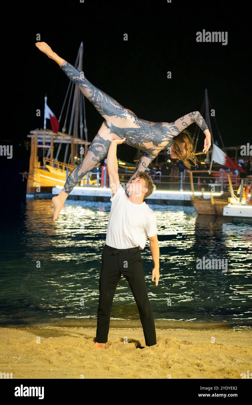 Un couple effectue une élégante pose de gymnastique dans la Katara Fan zone du Qatar, ajoutant de la grâce à l'atmosphère FIFA. Banque D'Images
