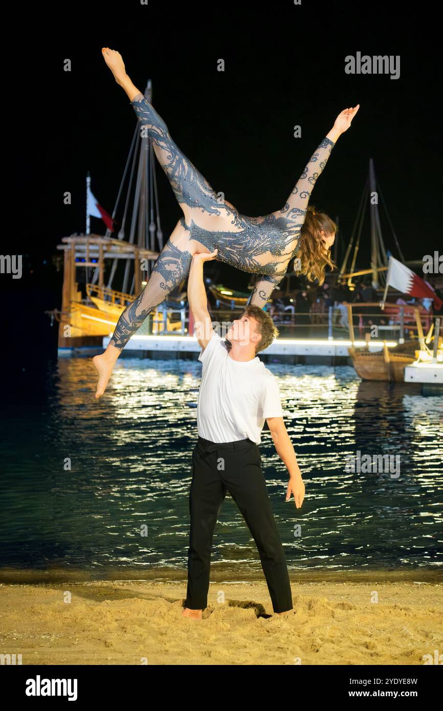 Un couple effectue une élégante pose de gymnastique dans la Katara Fan zone du Qatar, ajoutant de la grâce à l'atmosphère FIFA. Banque D'Images