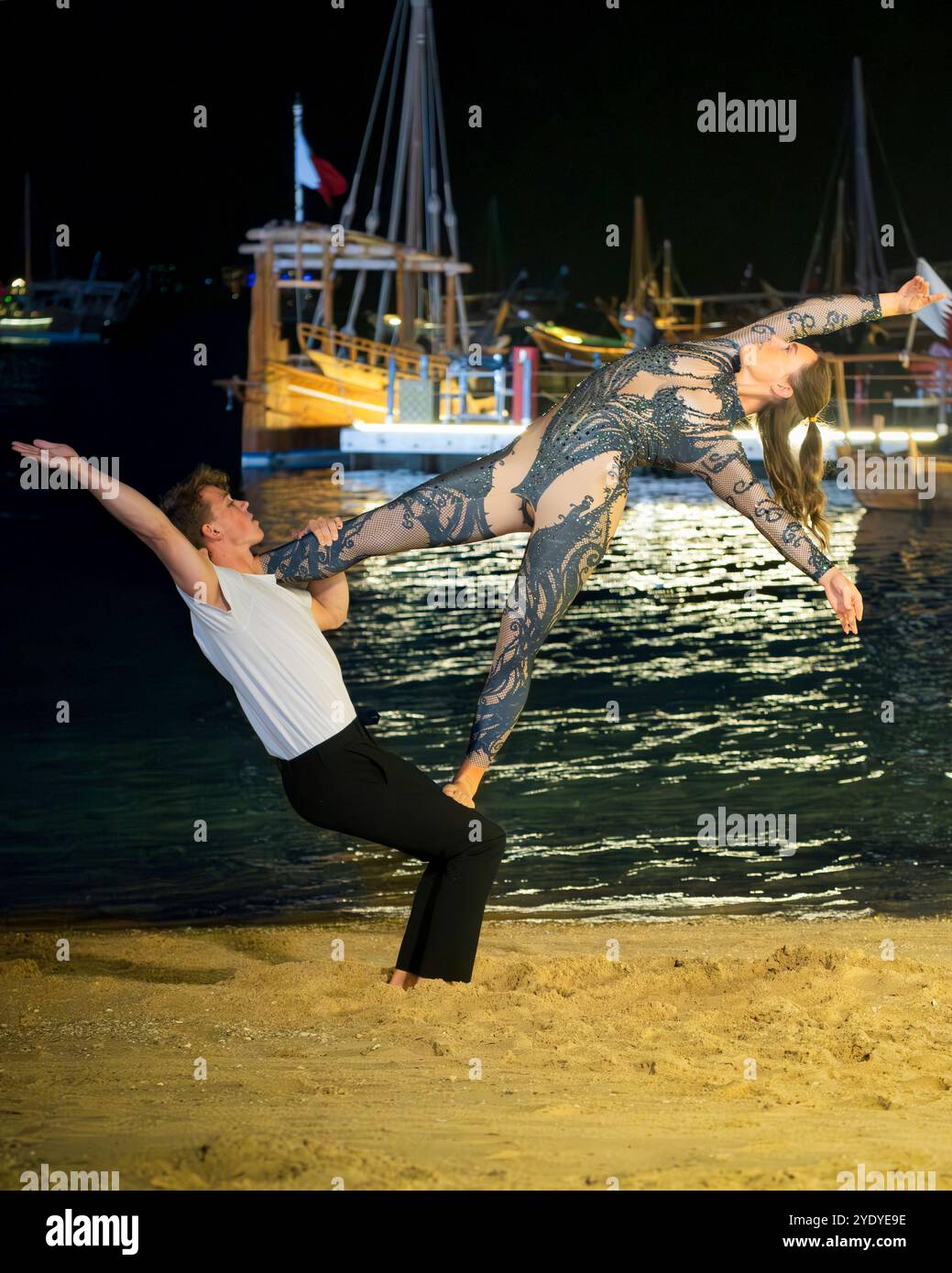 Un couple effectue une élégante pose de gymnastique dans la Katara Fan zone du Qatar, ajoutant de la grâce à l'atmosphère FIFA. Banque D'Images