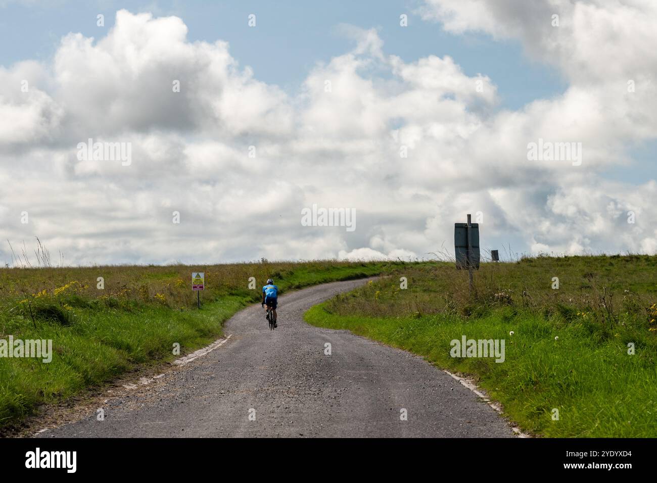 Un cycliste de route grimpe une colline dans la zone d'entraînement de l'armée britannique d'Imber Range sur la plaine de Salisbury dans le Wiltshire. Banque D'Images
