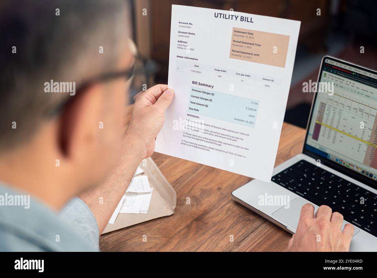 Homme examinant la facture de services publics tout en travaillant sur ordinateur portable. Concept de gestion des finances et du budget des ménages Banque D'Images