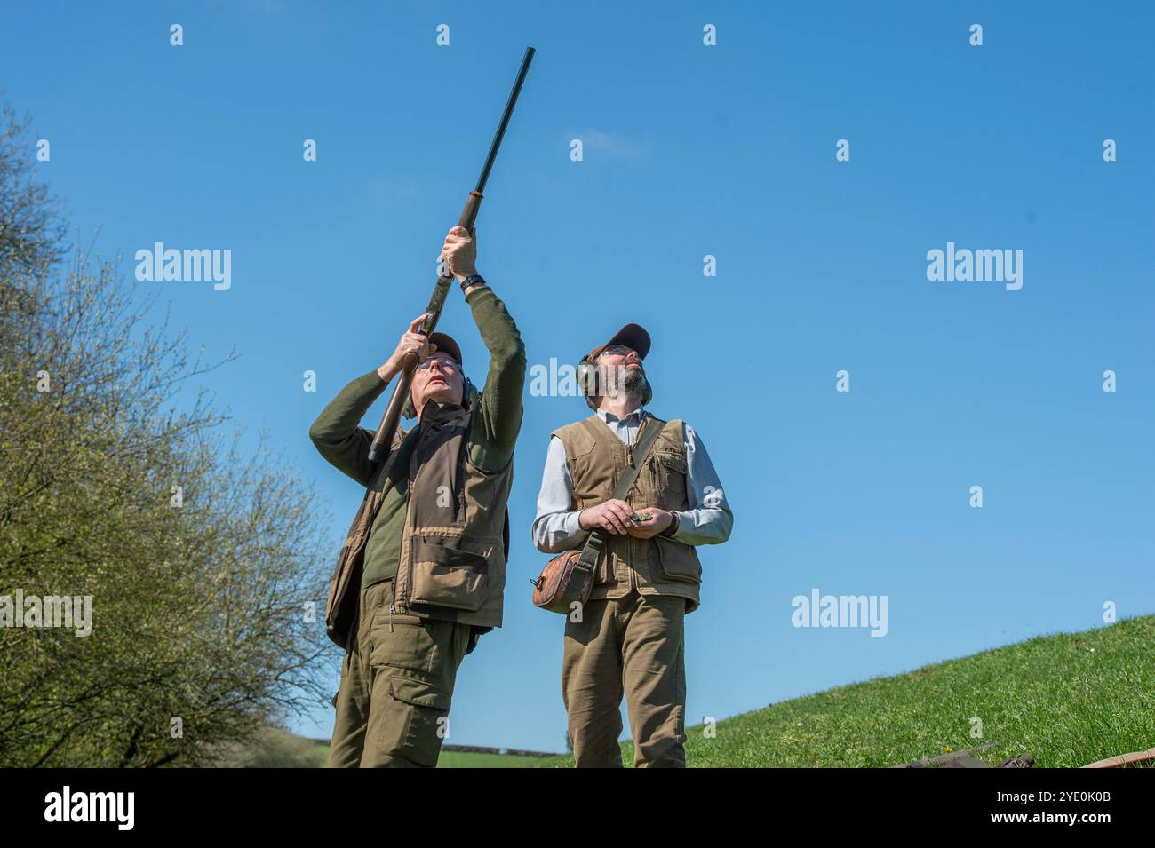 homme tirant sur des faisans, visant haut, avec sa chargeuse Banque D'Images