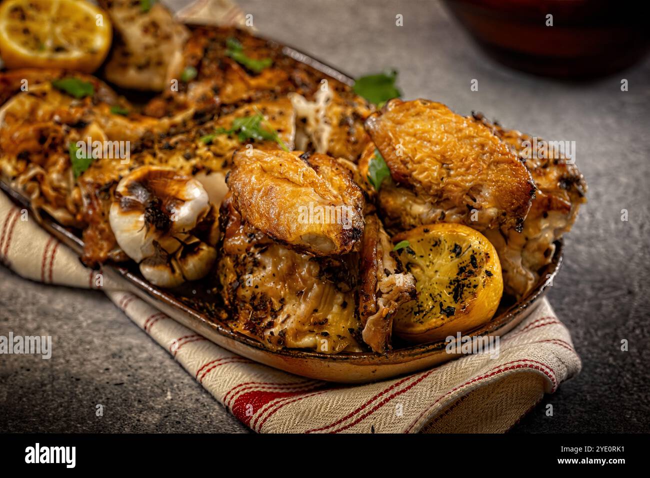 Assiette de poulet rôti entier garnie d'ail rôti et de citrons Banque D'Images